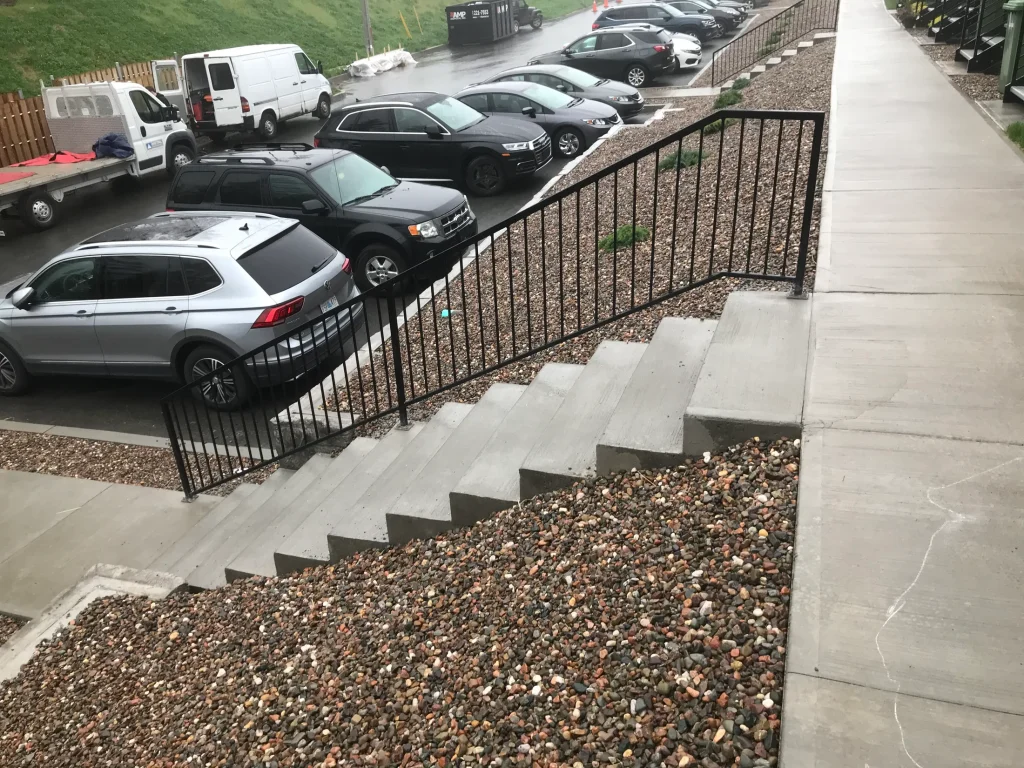 Black steel guardrail beside exterior concrete stairs by BriteArc Fabricators