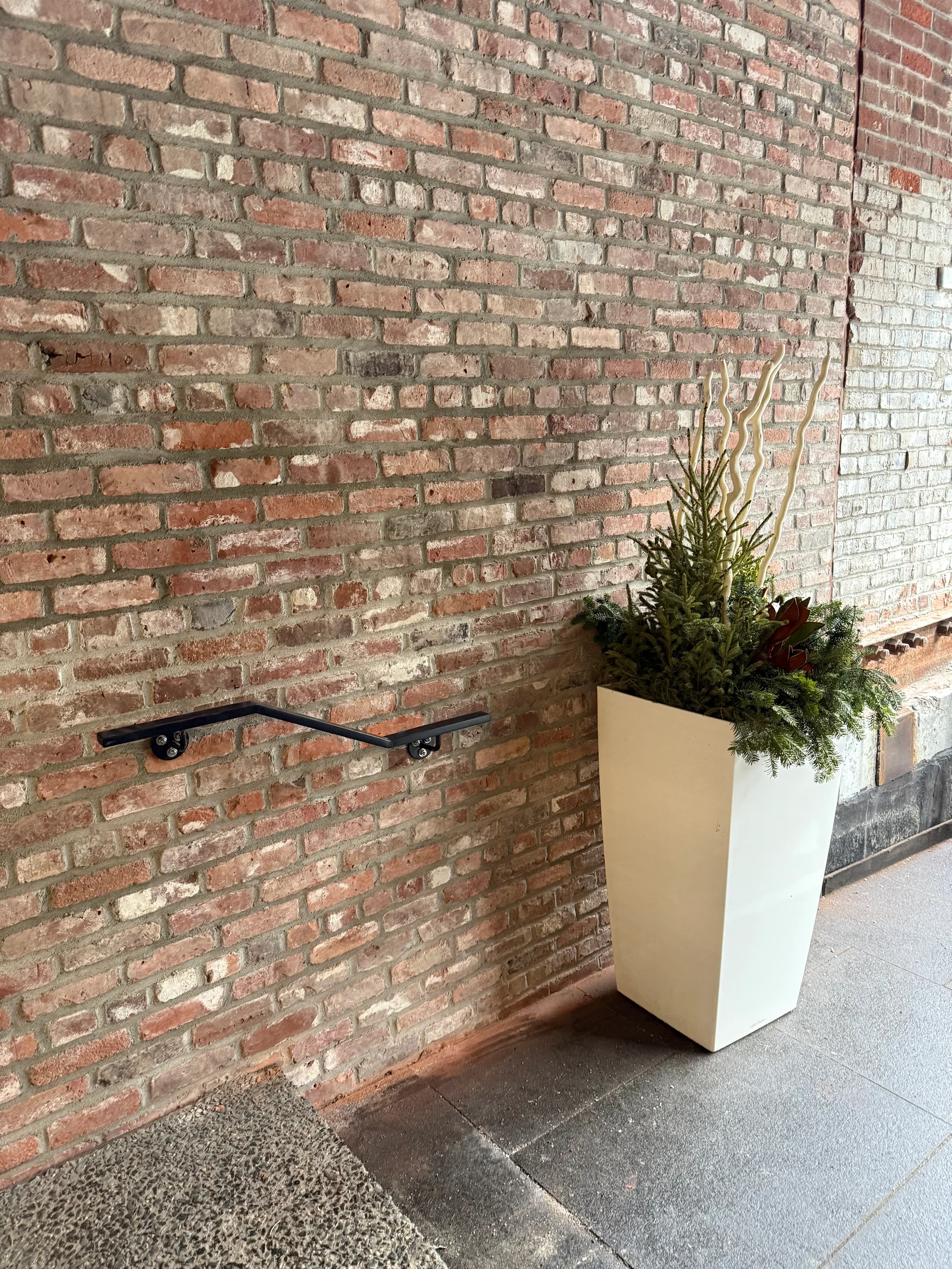 Completed wall-mounted handrail at a brick entrance by BriteArc Fabricators