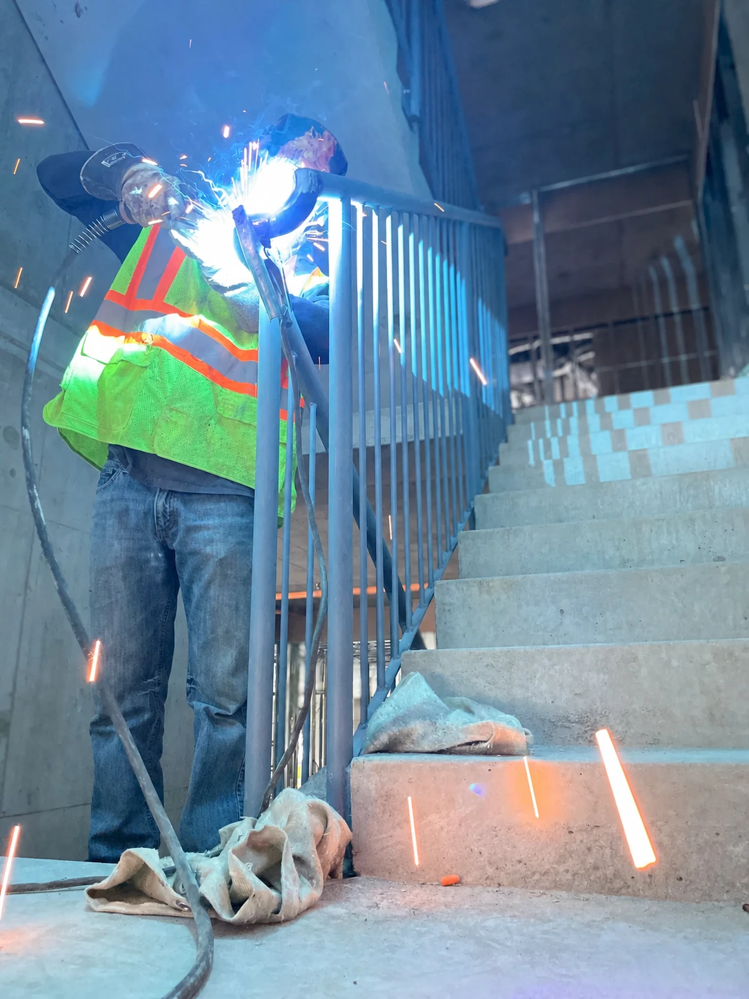 BriteArc fabricator welding a steel stair railing on site