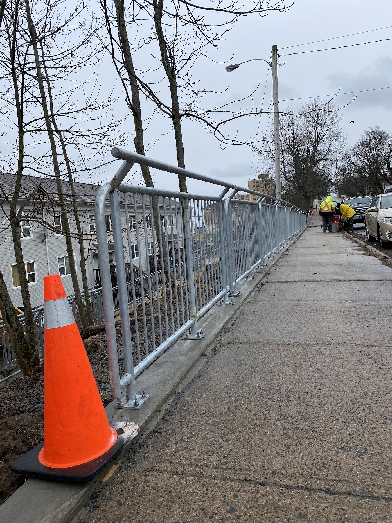 Long galvanized steel guardrail installed beside a public walkway