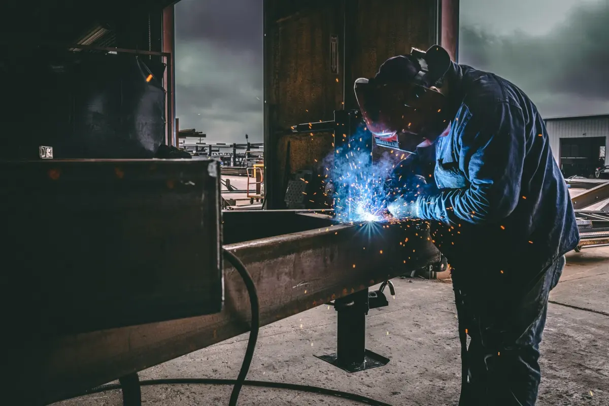 Welder joining structural steel in a fabrication shop