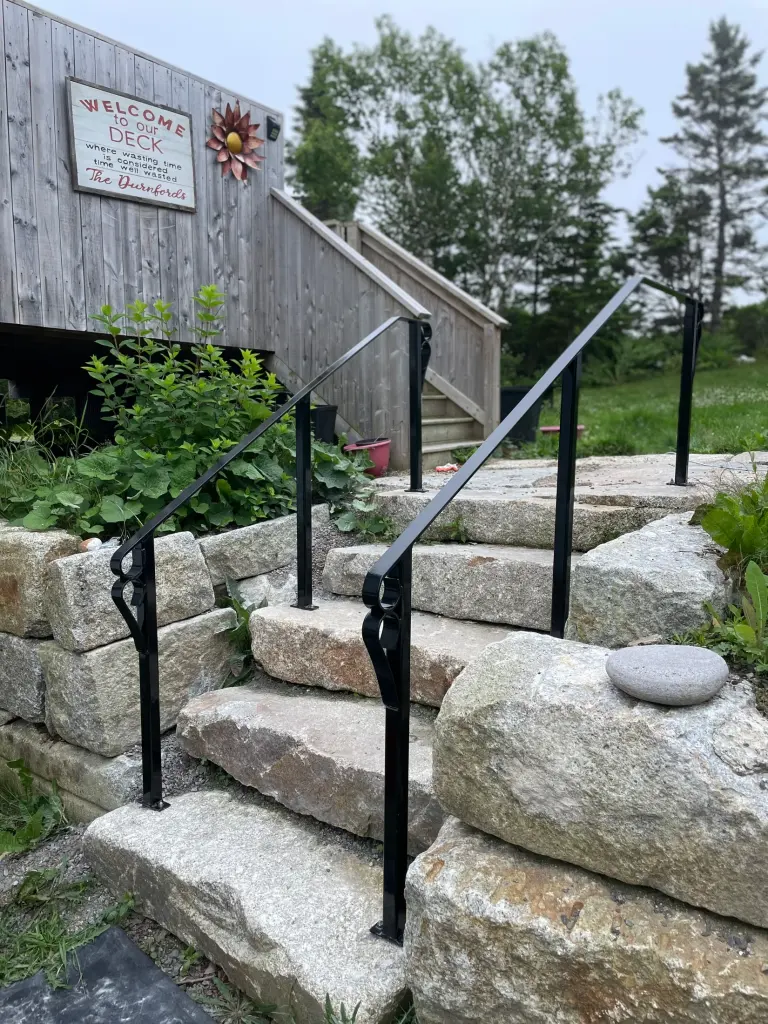 Handrails installed across a landscaped stone stair by BriteArc Fabricators