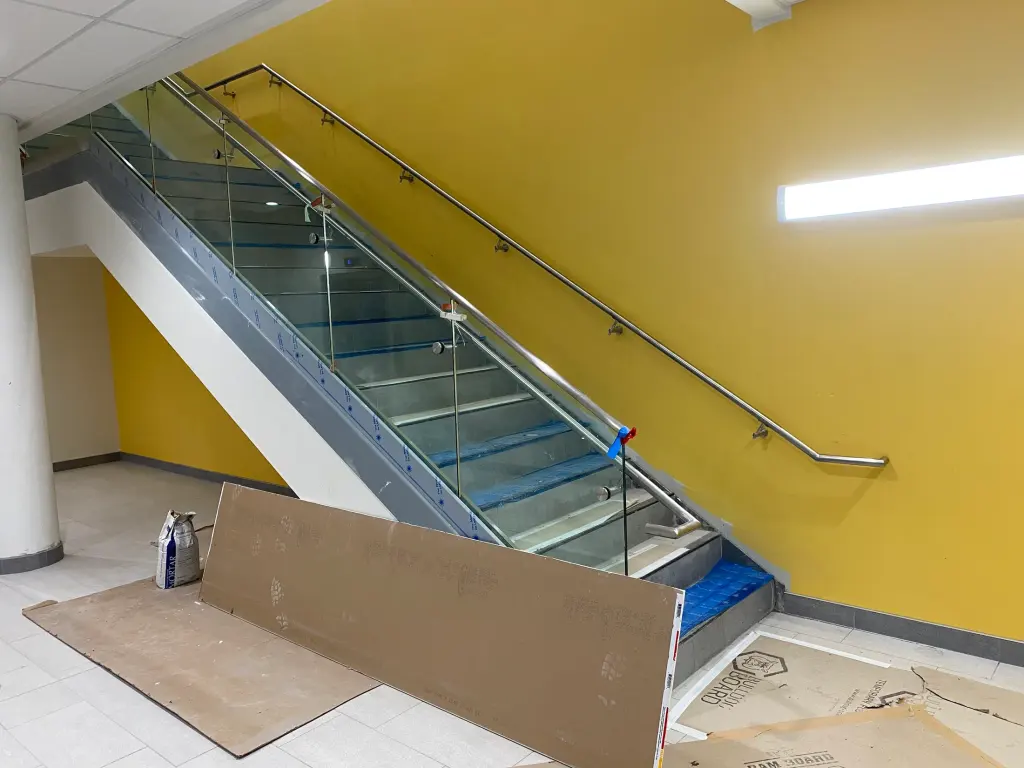 Glass guardrail and stainless handrail at an interior stair by BriteArc Fabricators