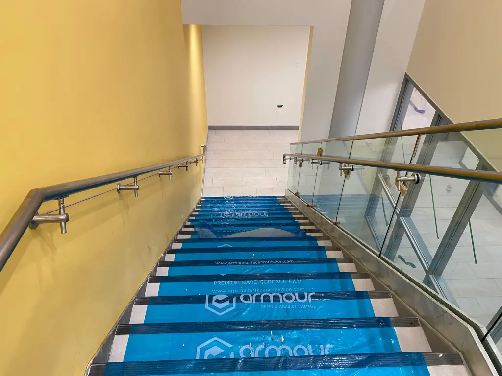 Completed stainless handrails and glass guards at an interior stair by BriteArc Fabricators